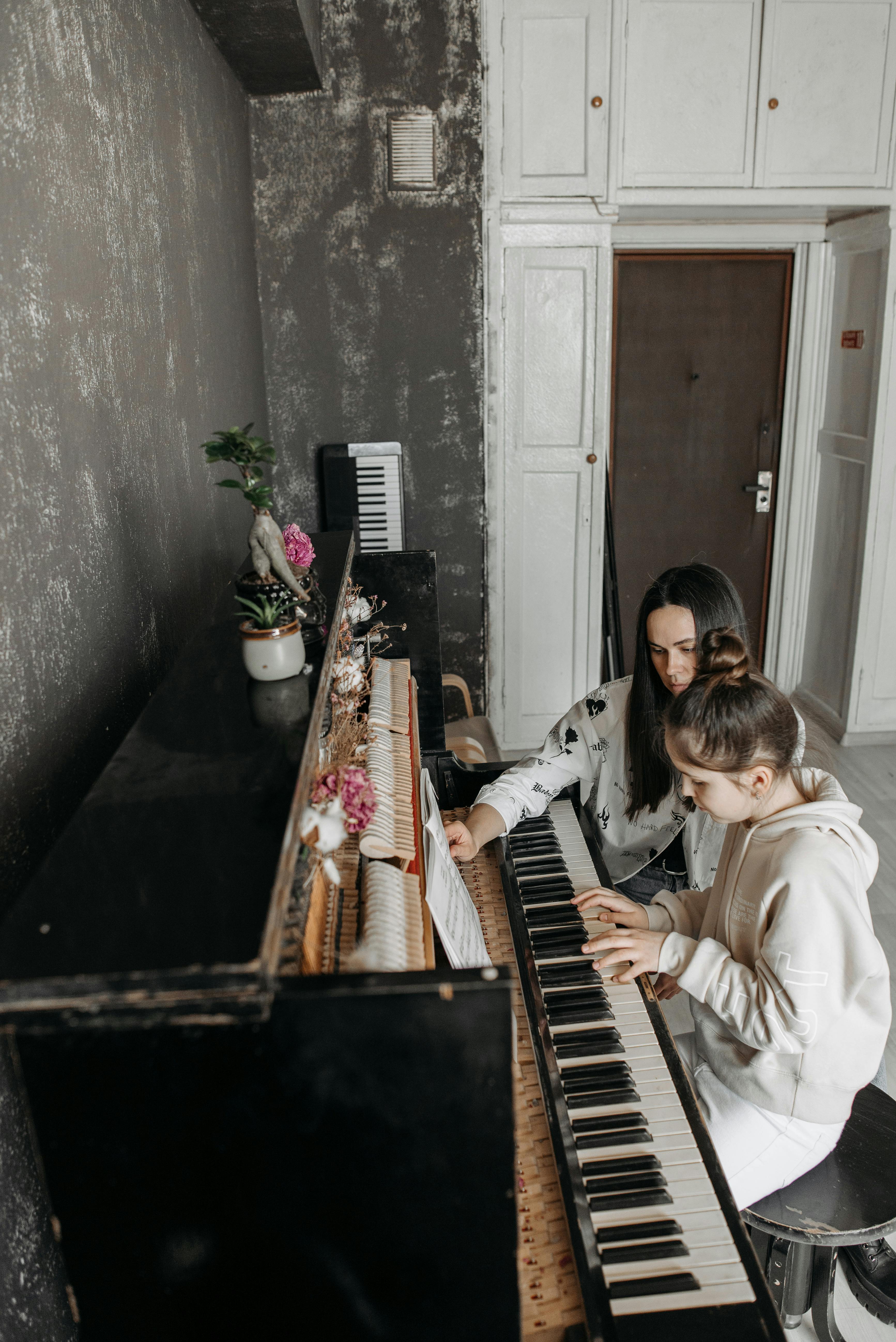 piano teacher and student sitting at a piano